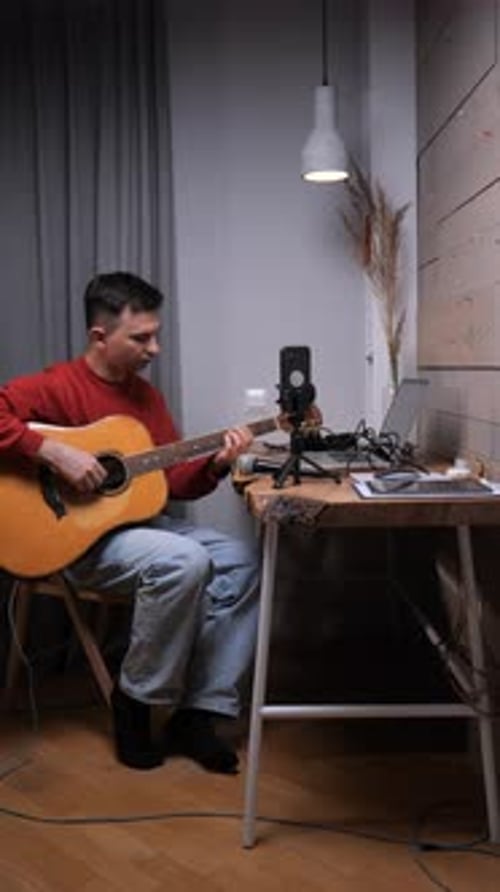 Vertical Video Man Recording a Video Playing His Acoustic Guitar in a Home Studio Using a Smartphone