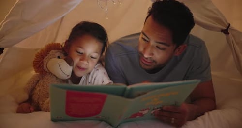 Dad Reading Story to Daughter in Fort at Night