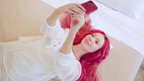 Woman with Pink Hair Takes Selfie on Bed