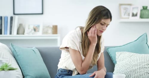 A young woman suffering with toothache at home
