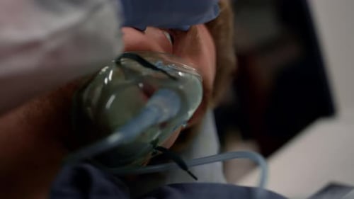 Paramedic examines unconscious man with oxygen mask in emergency medical service