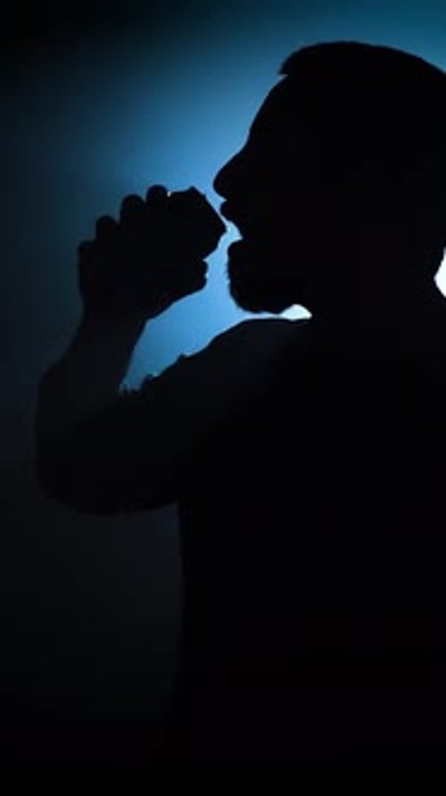 Silhouette of a Man Opening and Drinking From a Soda Can in Slow Motion