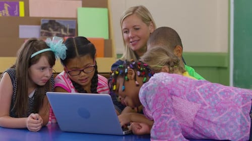 Teacher And Group Of Students Use Laptop In School Classroom