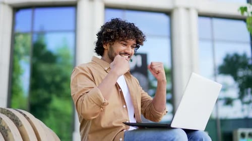 Excited Man Typing on Laptop Outdoors