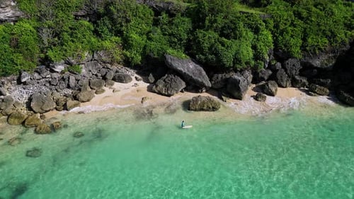Male Surfer in the Sea Near the Rocky Cliff