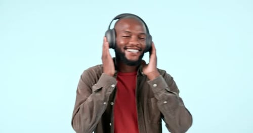 Headphones, dance or happy man streaming music to relax or freedom in studio on blue background
