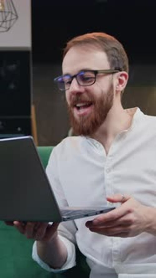 Enthusiastic Man Video Chatting on Laptop Indoors