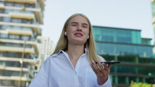 Young Woman Recording Voice Message on Smartphone in Modern City