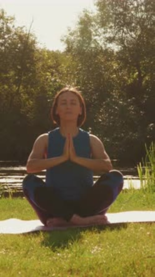 Young woman doing yoga exercise in park at summer sunny morning. Vertical video