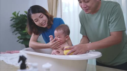 Loving Parents Bathe Their Baby in Small Tub