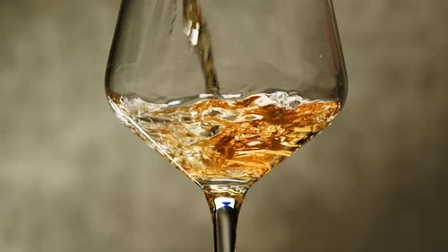 Orange or White Wine Bottle and Glass Against a Sunset in a Peaceful Vineyard Pouring of Ecological