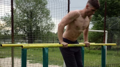 Muscular Man Doing Dips on Parallel Bars