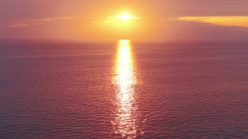 Golden sun setting over calm ocean waters casting a shimmering reflection on the sea