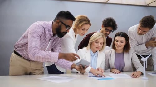 Multiethnic business team discusses wind turbine project in corporate office