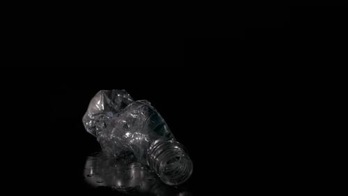 Crushed Plastic Bottle on Black Reflective Surface
