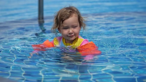 Girl Swims Around Kidfriendly Section of Pool in Colorful Floaties