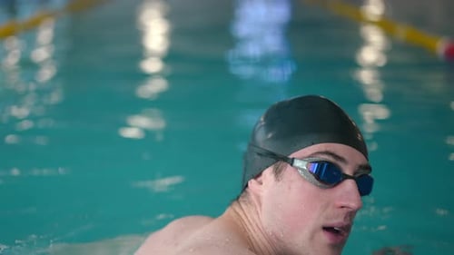 Vista trasera: Primer plano, joven deportista buceando bajo el agua, natación braza en cámara lenta