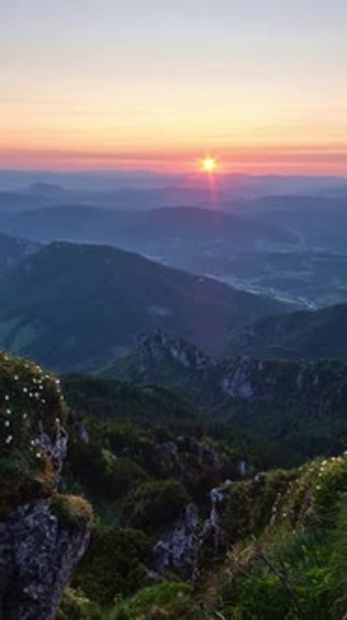 Coucher de soleil sur un paysage montagneux avec un village lointain en mode panoramique