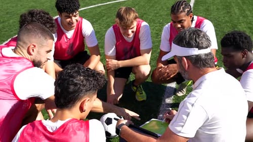 Soccer Coach Discussing Game Strategy with Team During Training