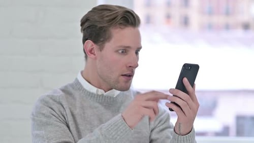 Man Reacts to Phone Message in Shock