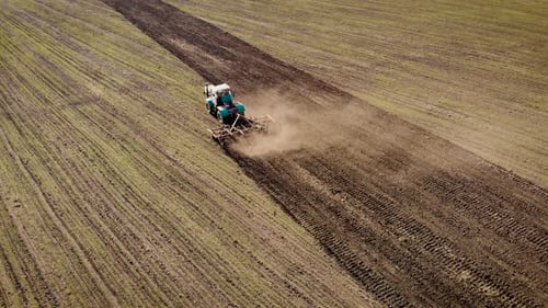 Aerial Drone View of Large Vintage Tractor with Wide Cultivator Plows Ground in Field for Sowing