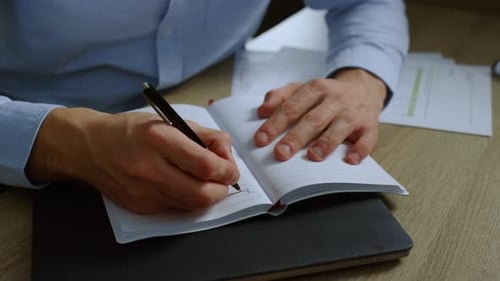 Man Writing in Notebook in Bright Office