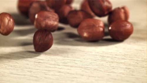 Hazelnuts Falling onto a Light Wooden Surface