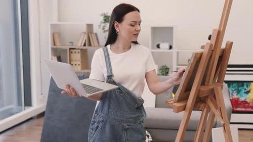 Woman Painting Art at Home While Using Laptop