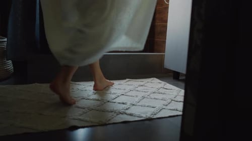 Woman Steps Out of Shower in Dimly Lit Bathroom