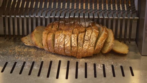 Loaf of Bread Being Sliced by Machine