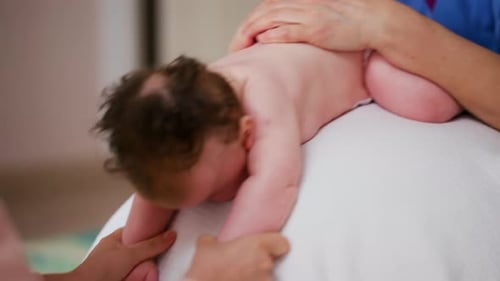 Infant having back massage in a bright environment