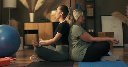 Two Women Meditating Back to Back at Home