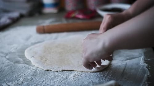 Hands Rolling Out Dough on a Floured Surface