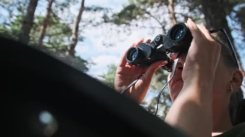 Woman Looking Through Binoculars in a Forest