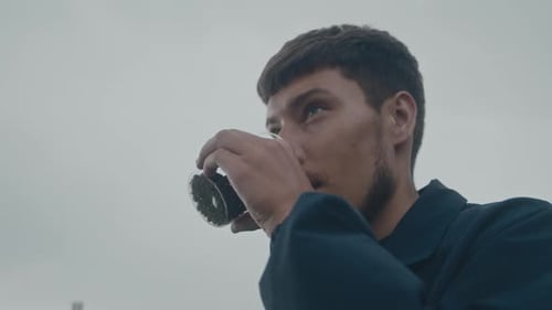 Man Drinking From Glass in Urban Setting