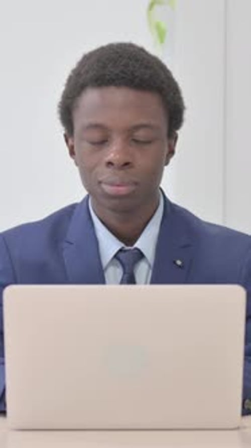 Young Man in Suit Gives Thumbs Up at Desk