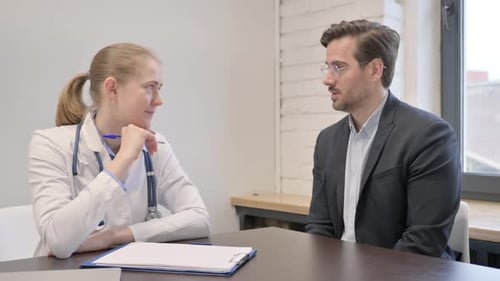 Female Doctor Listening Male Patient in Clinic
