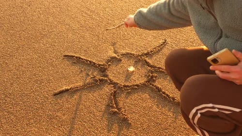 Sand Drawing Wave Person Creates Sun on Beach at Golden Hour Then Washes Away