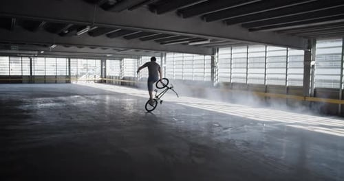 Young Adult Performing BMX Bike Trick in Garage