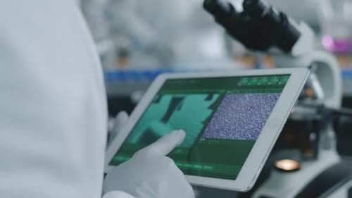 Científico anónimo sostiene una tableta con una imagen microscópica de una muestra en el laboratorio