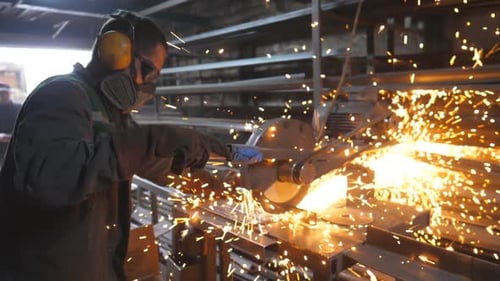 Craftsman with Circular Saw Sawing Steel in Workshop