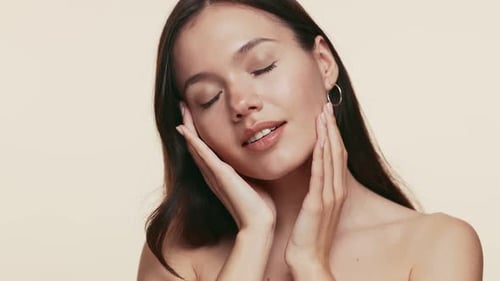 Attractive Woman Touches Her Face in Studio Setting