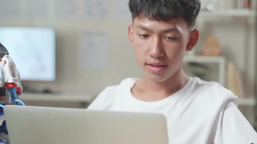 Close Up Of Asian Boy Working About A Cyborg Hand On A Laptop At Home