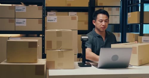 Man Scanning Boxes with Barcode Scanner in Warehouse