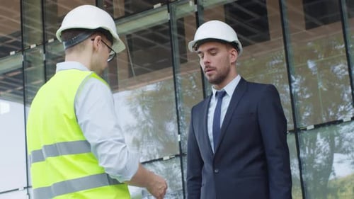 Businessman and Engineer in Hard Hats Having Agreement Handshake on Construction Site.