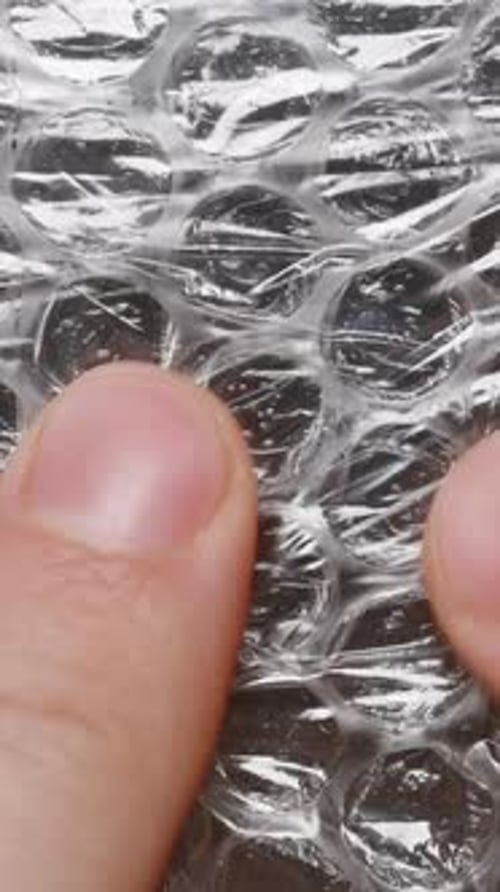 Vídeo vertical. Primer plano de los dedos masculinos presionando el plástico de burbujas, centrándose en el tacto