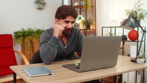 Man Working on Laptop at Desk in Home Office