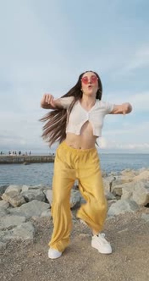 Enthusiastic Female Dancer Wearing Sunglasses While Dancing Outdoors By the Sea