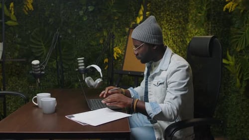 Blogger Using Laptop and Writing Podcast Script in Recording Studio