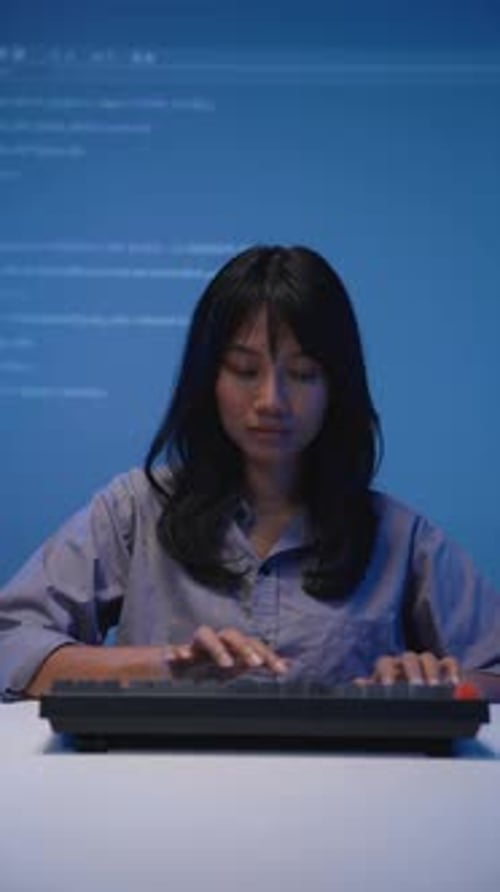 Asiatische Programmiererin in blauem Hemd beim Programmieren